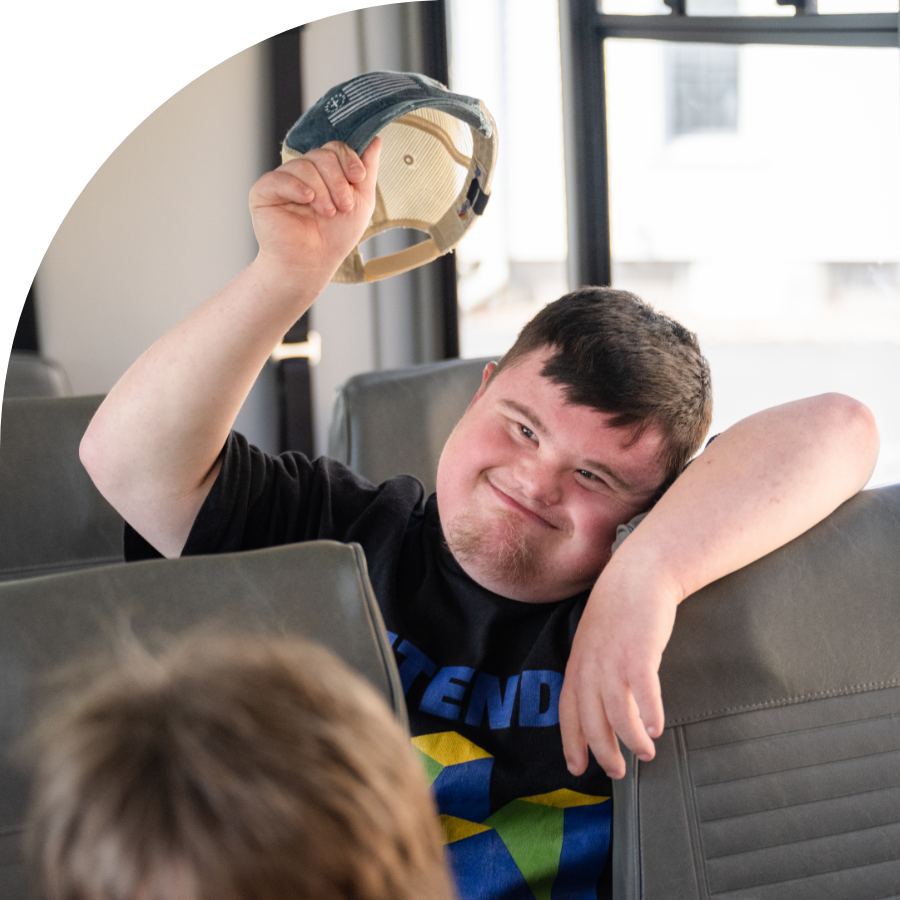 River Valley Special Rec participants smiles and waves hat in the air on the bus while riding to a fun program.